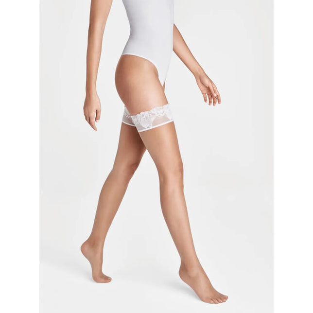 Model draagt Wolford Nude 8 Lace stay-up kousen in nude, transparant met een brede witte kanten boord. - Jambelles