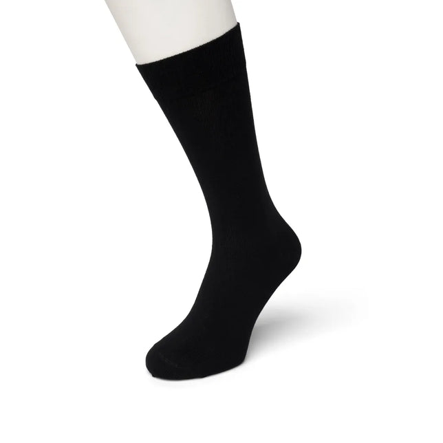 Bonnie Doon Cotton Sock BD 632401 herensok in effen zwart, gedragen op een witte paspopvoet. - Jambelles