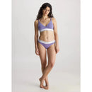 Model draagt paarse Calvin Klein dames bikinislip 0000F3787E met witte logoband en bijpassende bralette. - Jambelles