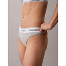 Model draagt een grijze Calvin Klein dames string thong met witte elastische logoband en bijpassende bralette. - Jambelles