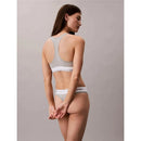 Model draagt een grijze Calvin Klein dames string thong met witte elastische logoband en bijpassende bralette. - Jambelles