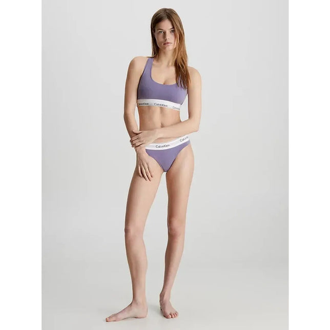 Model draagt paarse Calvin Klein Icon Cotton Modal bralette met brede bandjes en witte logoband. - Jambelles
