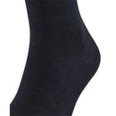 Falke herenkniekousen Energizing Wool 15530 in zwart met medium compressie, afgebeeld bij een man in blauw pak en vliegtuig. - Jambelles