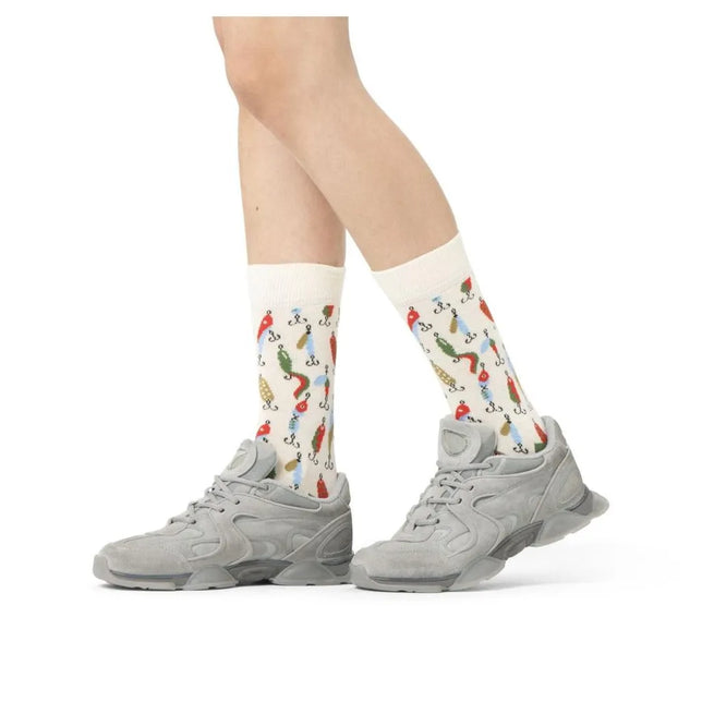 Happy Socks Fishing Gear fantasiesokken in gebroken wit met kleurrijke vishaken en kunstaas, gedragen met grijze sneakers. - Jambelles