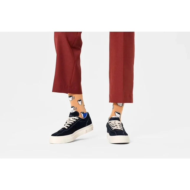 Happy Socks fantasie sokken in oranje met witte en blauwe theekopjes, gedragen bij een rode broek en zwarte sneakers. - Jambelles