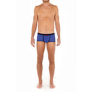 Model draagt de turquoise HOM heren boxer trunk HO1 Plume Up 402373 met zwarte tailleband, biezen en roze detail. - Jambelles