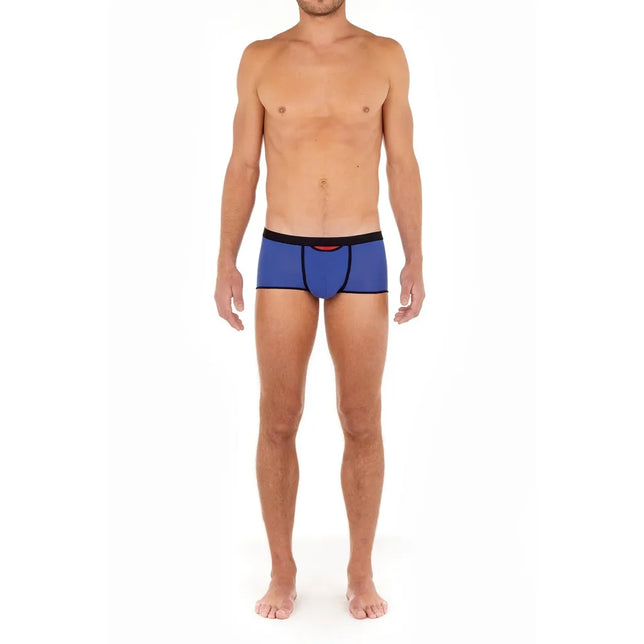 Model draagt de blauwe HOM heren boxer trunk HO1 Plume Up 402373 met zwarte tailleband, biezen en rood detail. - Jambelles