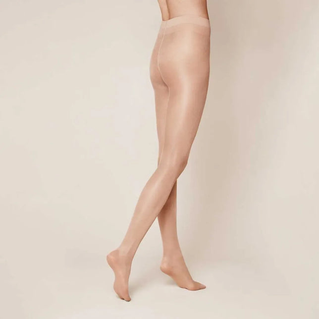 Kunert Dames Panty Satin Look 20 110333000 in huidkleur, transparant en glanzend, zijaanzicht met gekruiste benen. - Jambelles