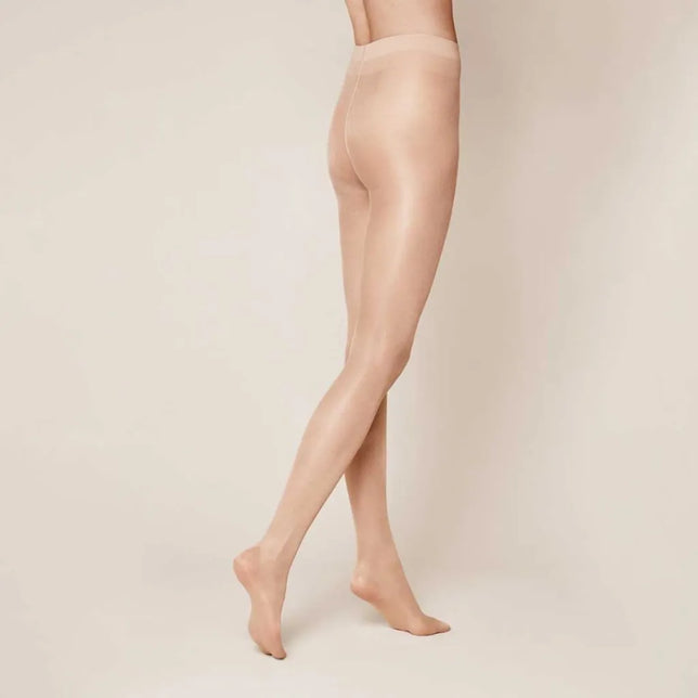Kunert damespanty Satin Look 20 in huidkleur, transparant en glanzend, gedragen door een model met gekruiste benen. - Jambelles