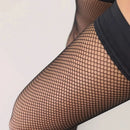 Kunert dames stay-up kousen Raffinesse Net in zwart, gedragen op gekruiste benen met fijnmazig netpatroon. - Jambelles
