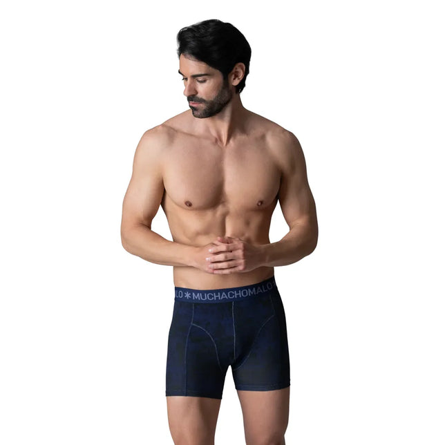Herenmodel draagt een donkerblauwe Muchachomalo-boxershort met aansluitende pijpen en elastische logoband. - Jambelles