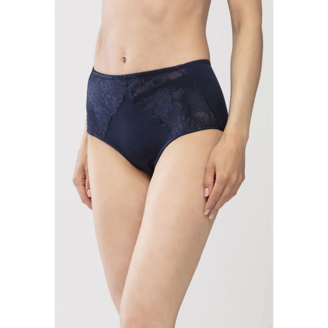Model draagt de Mey dames taillenslip 79285 in donkerblauw, met hoge taille en kanten inzetstukken aan de voorkant. - Jambelles
