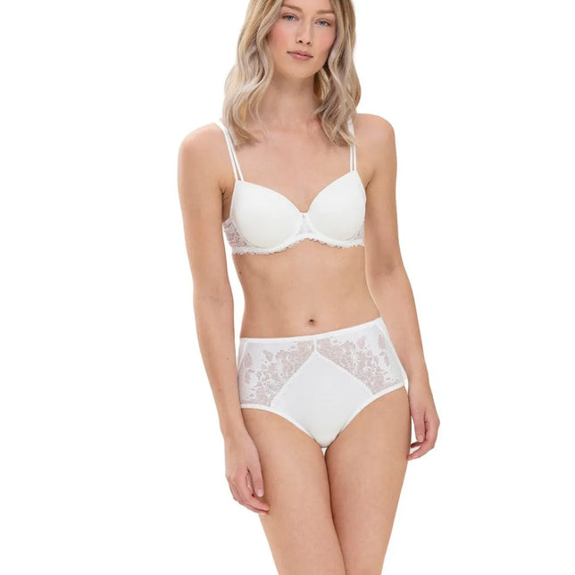 Model draagt de witte Mey Dames Taillen-Slip 79285 met hoge taille, glad voorpand en transparante bloemenkant. - Jambelles