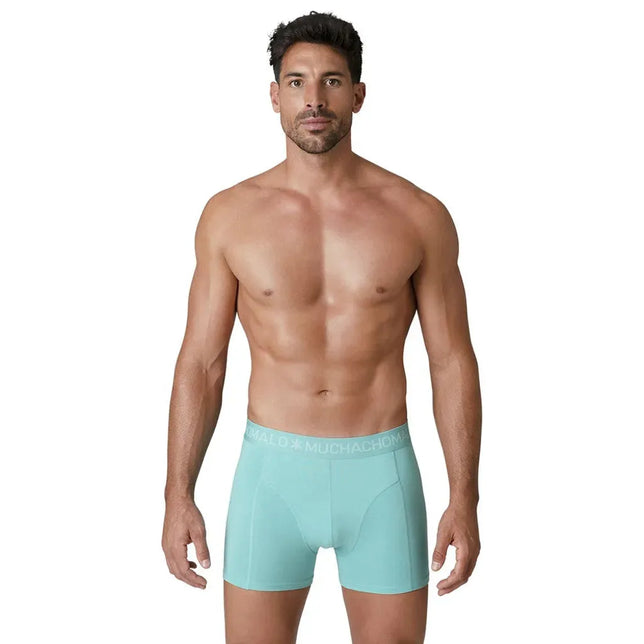 Model draagt een turquoise Muchachomalo herenboxer uit de Solid U-Solid1010 10-pack, met logoband en korte pijpen. - Jambelles