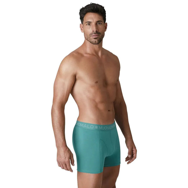Muchachomalo herenboxer in turquoise, gedragen door een model, met aansluitende pijpen en elastische logoband. - Jambelles