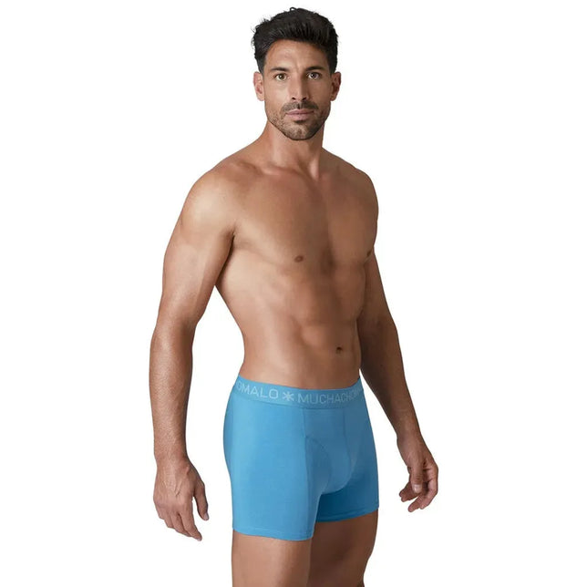 Model draagt een lichtblauwe Muchachomalo herenboxer uit de Solid U-Solid1010 10-pack met logoband en lange pijpen. - Jambelles