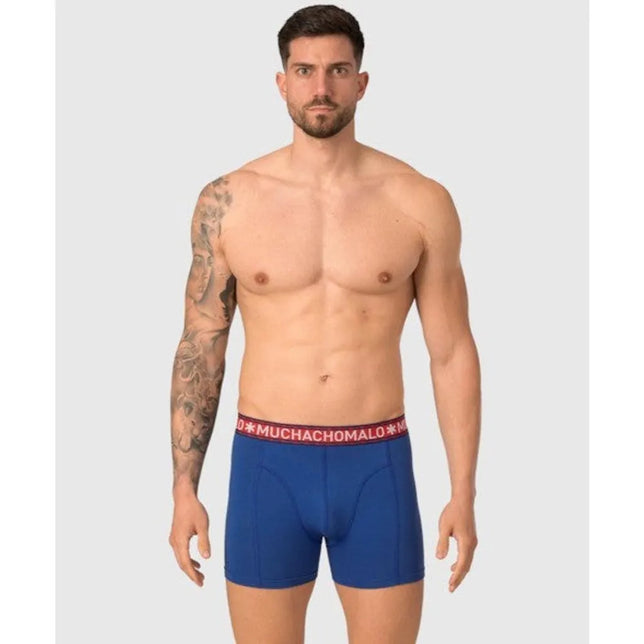 Model draagt een blauwe Muchachomalo herenboxer Solid1010 met korte pijpen en rode logoband. - Jambelles
