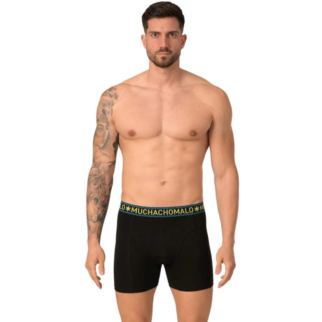 Model draagt een zwarte Muchachomalo herenboxer SOLID1010 met turquoise tailleband en geel merklogo. - Jambelles