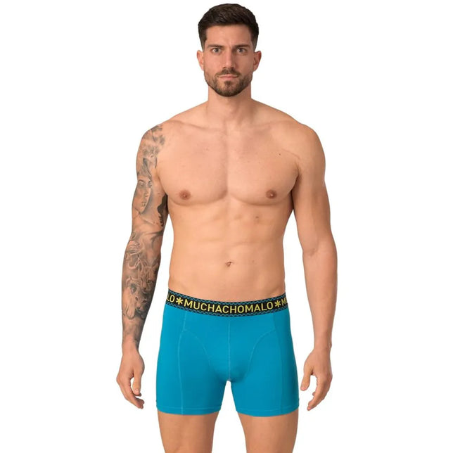 Muchachomalo herenboxer SOLID1010 in turquoise, gedragen door een model, met zwarte logoband en gele letters. - Jambelles