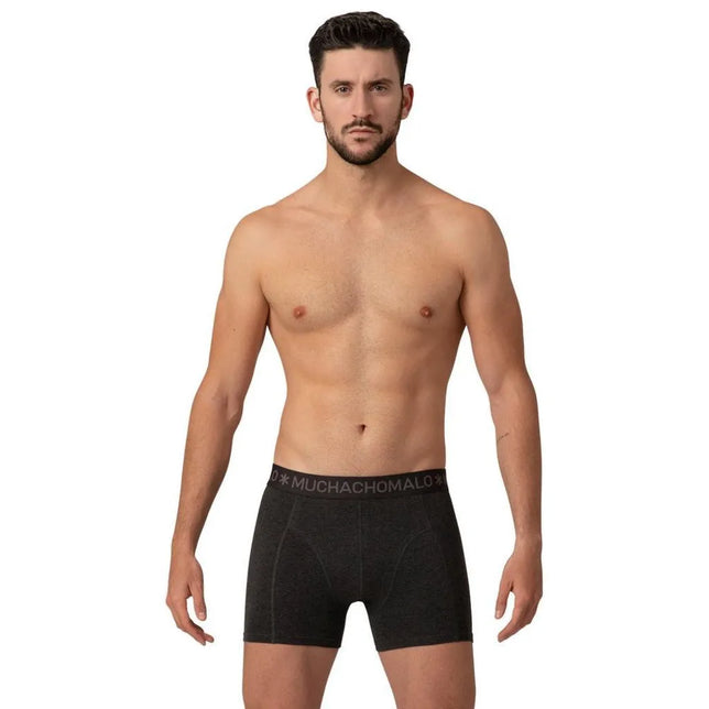 Model draagt een zwarte Muchachomalo herenboxer Short Solid SOLID1010 met logoband en zichtbare siernaden. - Jambelles