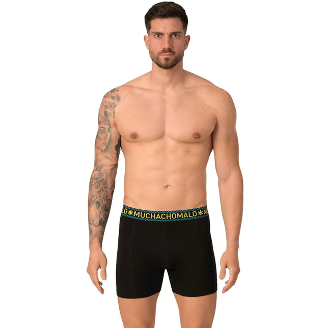 Model draagt een zwarte Muchachomalo herenboxer met korte pijpen en elastische logoband in blauw en geel. - Jambelles