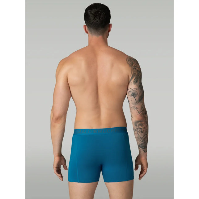Achteraanzicht van model in petrolblauwe Muchachomalo herenboxer met aansluitende pijpen en elastische logoband. - Jambelles
