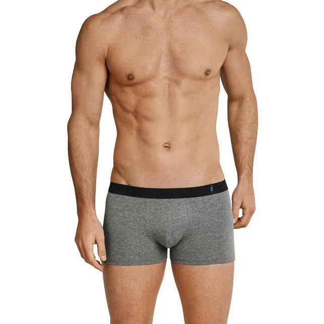 Model draagt een grijze Schiesser herenboxer Low Rise met korte pijpen, zwarte tailleband en klein blauw logo. - Jambelles