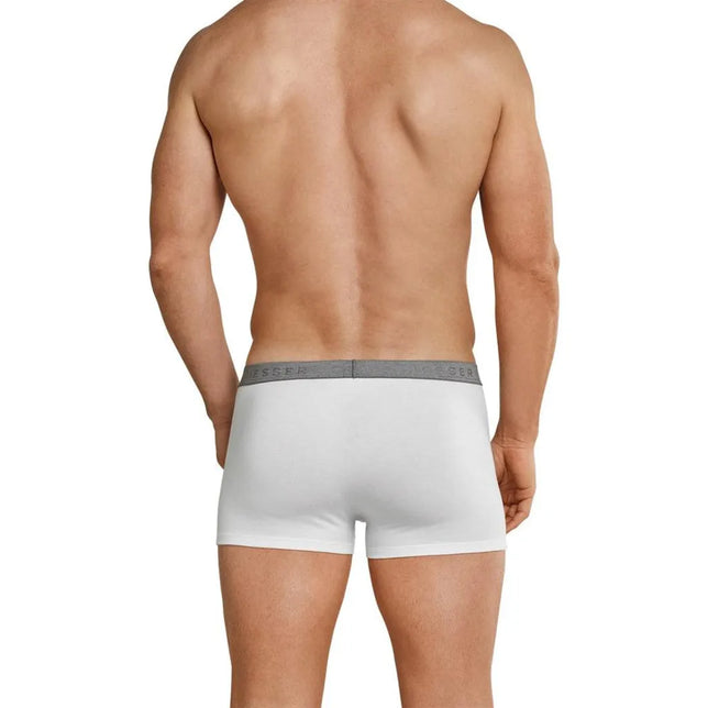 Achteraanzicht van model in witte Schiesser herenboxer Low Rise met korte pijpen en grijze logotailleband. - Jambelles