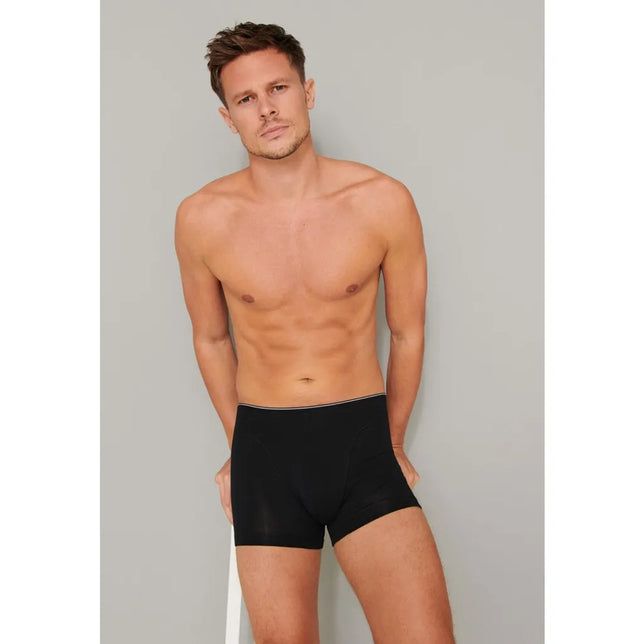 Schiesser heren boxershort 174004 in zwart, gedragen door een model, met korte pijpen en smalle witte bies aan de taille. - Jambelles