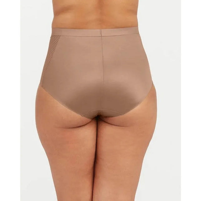 Model draagt een taupe Spanx Thinstincts 2.0 dames slip met hoge taille, gladde afwerking en geribbeld zijpaneel. - Jambelles
