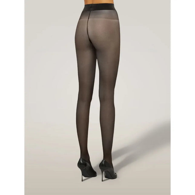 Wolford damespanty Satin Touch 20 in zwart, transparant met brede tailleband, van achteren gedragen met pumps. - Jambelles