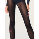 Model draagt Wolford Travel Leg Support panty 14622 in donkerpaars met subtiel diagonaal patroon en zwarte pumps. - Jambelles