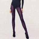 Model draagt Wolford Travel Leg Support panty 14622 in donkerpaars met subtiel diagonaal patroon en zwarte pumps. - Jambelles