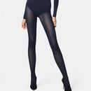 Model draagt Wolford Travel Leg Support panty 14622 in donkerpaars met subtiel diagonaal patroon en zwarte pumps. - Jambelles