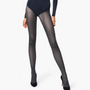 Model draagt Wolford Travel Leg Support panty 14622 in donkerpaars met subtiel diagonaal patroon en zwarte pumps. - Jambelles